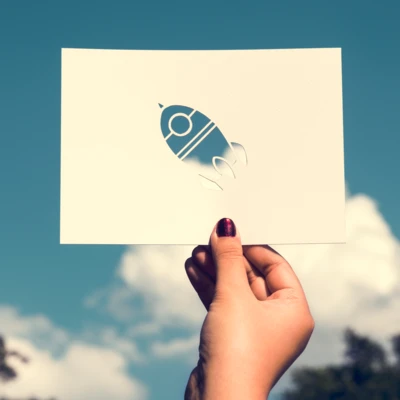 hand-hold-space-rocket-paper-carving-with-sky-background